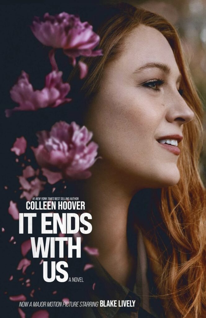 It Ends With Us 1 Book cover for "It Ends With Us" by Colleen Hoover. The cover features a photograph of a woman with long red hair smiling softly, facing right. Pink flowers are scattered across the image. Text at the bottom states the book is now a major motion picture.